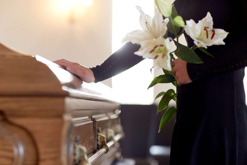 mujer con flores en ataud que sabe que no hacer en un funeral